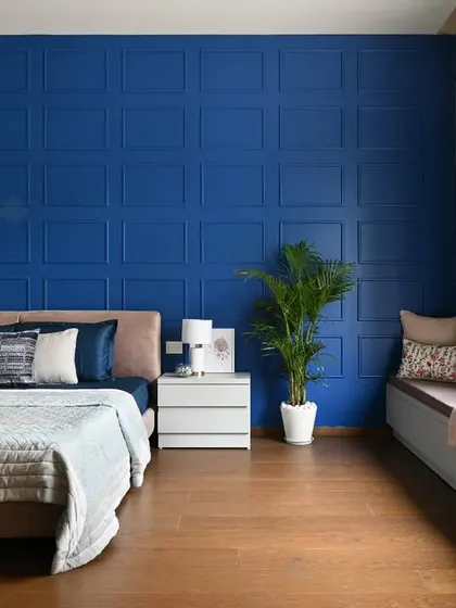 A wide shot of the master bedroom with the blue panelled wall, showing the spacious layout that includes a large bed and a cozy window seating area.