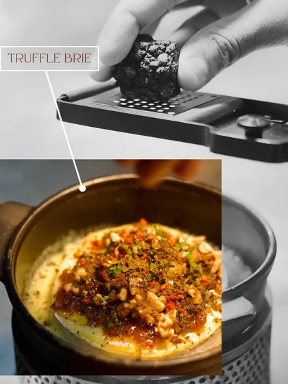A chef grates fresh black truffle over our warm, melty Truffle Brie. This is how we elevate a simple dish into something truly special, focusing on the power of a single, high-quality ingredient.