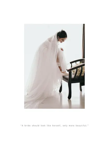 The bride adjusts her shoe, a classic getting-ready shot that is both elegant and real.