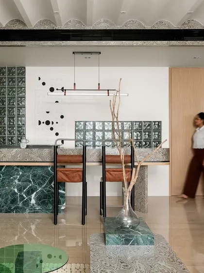 The breakfast counter, with its bold green marble base and textured veneer top, is a perfect example of how we use materials to create visually pleasing and functional spaces.