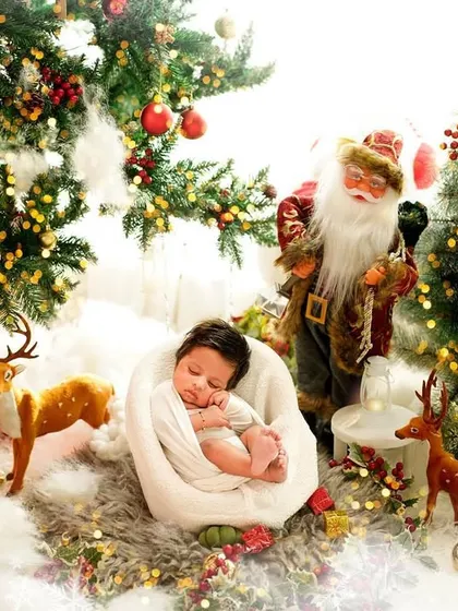 A magical newborn Christmas scene. This elaborate setup with Santa, reindeer, and festive trees creates a storybook image for your baby's first holiday season.
