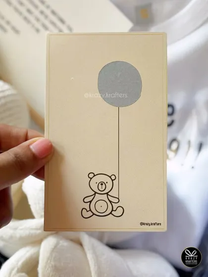 A fun scratch-off card is an interactive way to reveal the big news. This one, featuring a teddy bear, adds a playful element to your pregnancy announcement.