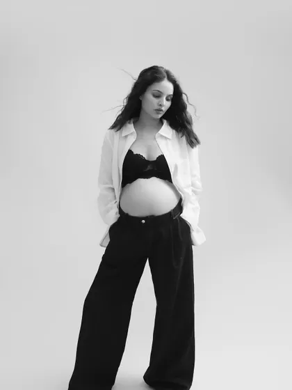 A striking and artistic black and white portrait. The focus is on her form and the quiet confidence she exudes, making for a powerful image of motherhood.