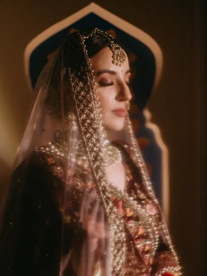 A stunning, softly lit portrait of a bride with her eyes closed, her face partially veiled, capturing a moment of serene beauty.