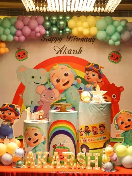 A full stage setup for a Cocomelon party in a banquet hall. The colorful balloon garland and large backdrop make a big impact in a larger space.