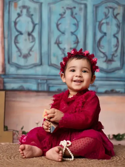 A vibrant portrait in a beautiful red dress, part of a multi-set first birthday celebration.