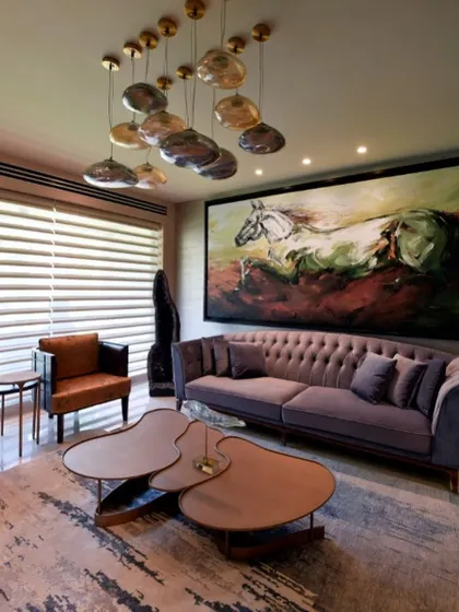 A detail of the living room, focusing on the tufted lavender sofa and a unique cluster of pendant lights. The organic shapes and soft colors contribute to the room's serene and artistic atmosphere.