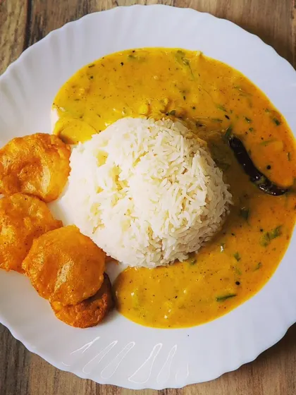 My go-to comfort food, Punjabi Kadhi Chawal. This is a beautifully plated meal of steamed rice surrounded by a tangy yogurt and gram flour curry, served with crispy homemade aloo pakoras on the side.