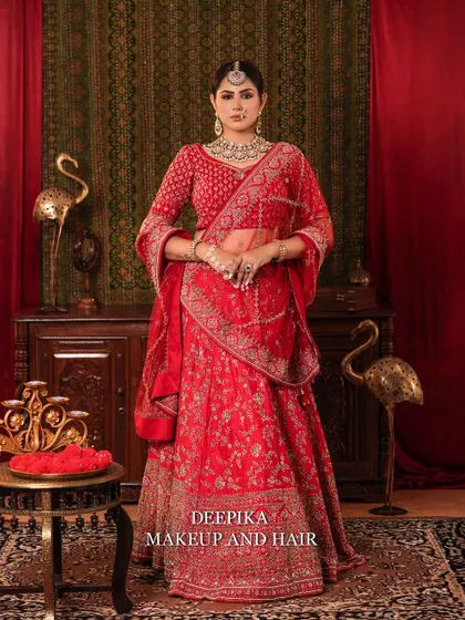 A full-length shot of the bride standing against a rich, traditional backdrop. The red of her lehenga stands out beautifully.
