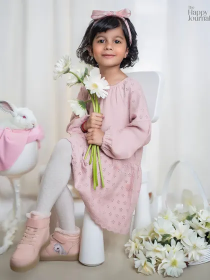 A little girl in a pink dress sits with a live bunny and a basket of flowers. A truly sweet and gentle spring-themed portrait.