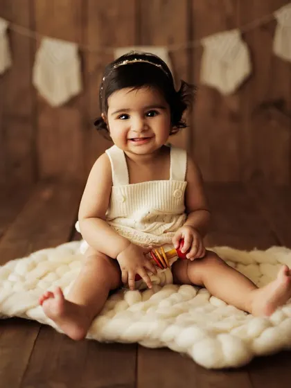 Another angle from a sweet sitter session, showing the baby's joyful expression as she plays with a toy.