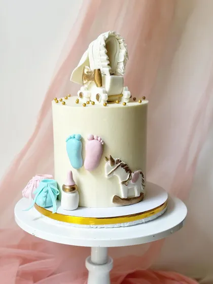 A duplicate image of the adorable gender reveal cake, showcasing the detailed baby-themed decorations on a clean white buttercream base.
