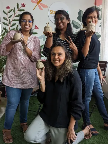 A group of friends proudly showing off the pottery pieces they created in our hand-built pottery workshop. It's a fun and rewarding group activity.