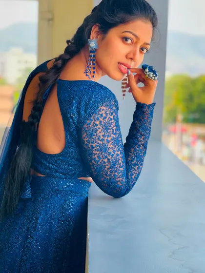 A playful and stylish pose in a blue sequin lehenga with a keyhole back and braided hair.