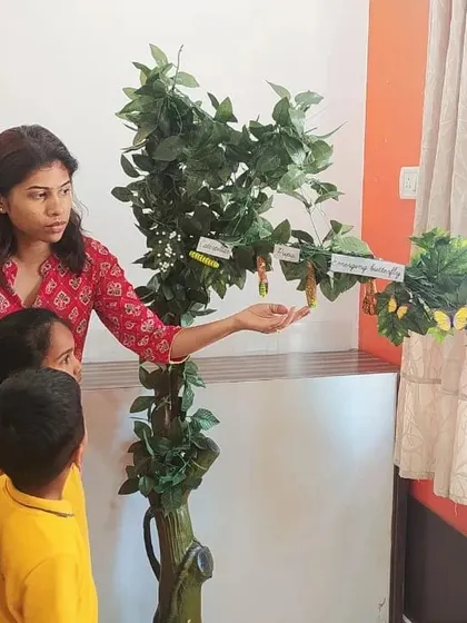 A teacher uses a model to explain the life cycle of a butterfly to an engaged group of children. These visual aids are crucial for helping children understand complex biological transformations.