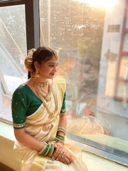 A wider shot of the South Indian bride, capturing the elegance of her posture and the beautiful fall of the Kasavu saree.