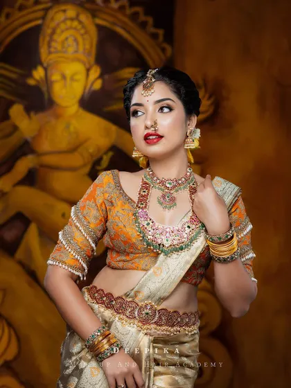 A side profile showcasing the intricate hairstyle and the beautiful fall of the saree. The pop of red in her lipstick perfectly ties the whole look together.