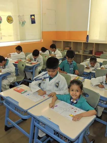 A wide shot of the classroom shows all students diligently working on their drawings for the Gandhi Jayanti celebration.
