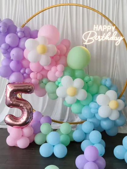 A beautiful pastel daisy-themed balloon arch for a 5th birthday, perfect for a spring or garden party.