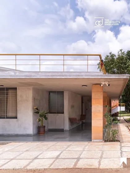 The exterior of "Aamra," showing the flat roof terrace accessible via an external staircase. This elevated space provides panoramic views of the surrounding mango farm and the Banthamari state forest beyond.