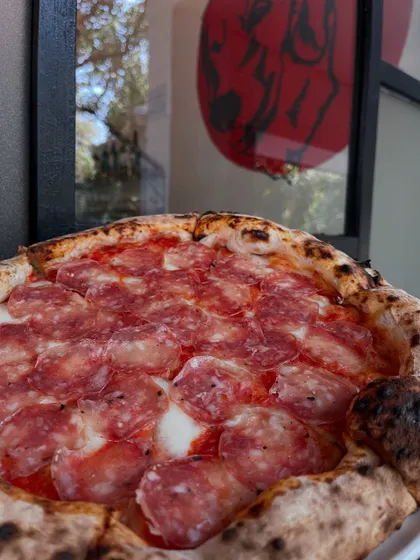 A close-up of our salami pizza, showcasing the quality of the cured meat we use.