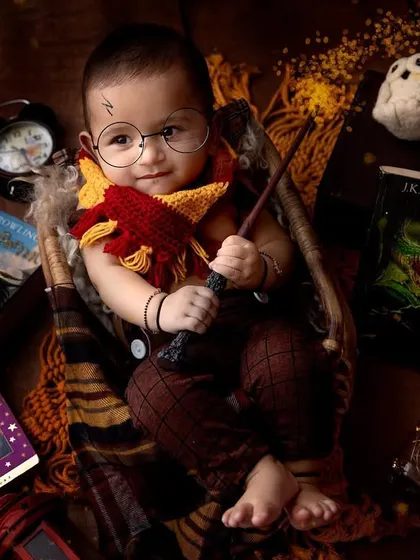 Wingardium Leviosa! This Harry Potter theme is a favorite for so many parents, and look at this little wizard. With the Gryffindor scarf, round glasses, and magic wand, this studio portrait brings a little bit of Hogwarts magic to life.