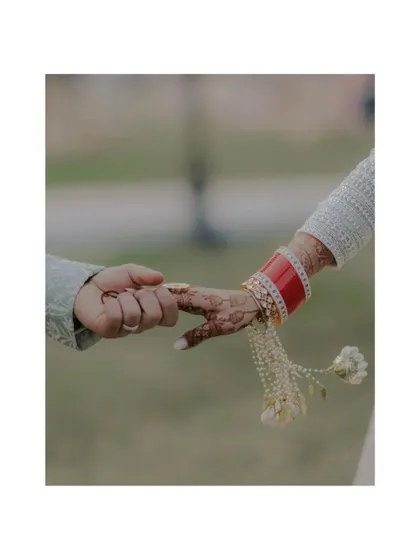 A close-up shot of a bride and groom's hands, showing the engagement ring and the bride's traditional chooda. A beautiful detail shot that tells a story.