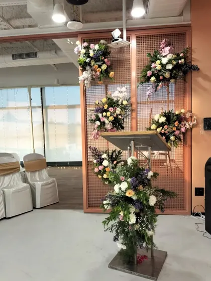 A decorated podium serves as a focal point for speeches and announcements during a launch event. We adorned this lectern and the surrounding area with coordinated floral arrangements to create a visually appealing stage for speakers.