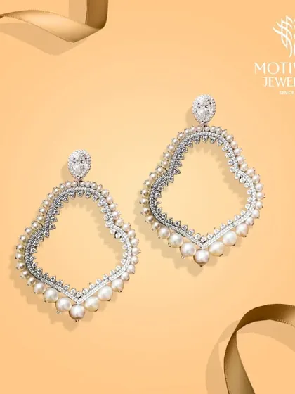 Large, open-frame earrings outlined with sparkling diamonds and delicate pearls. The design is light and airy, yet makes a significant style statement.