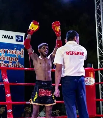 The moment of victory. Our fighter's hand is raised by the referee after a dominant performance in an international Muay Thai fight.