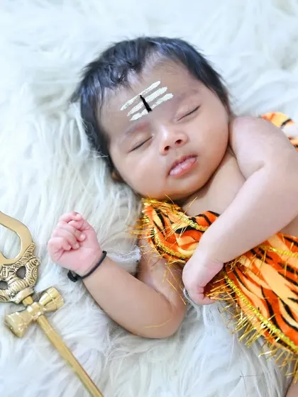 Another take on the baby Shiva theme for a newborn shoot. This little one is dressed in a tiger-print wrap and has the sacred vibhuti on his forehead, looking so serene on a soft white fur blanket.