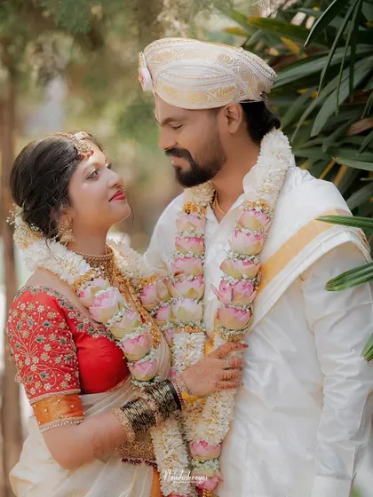The couple shares a loving look, their garlands connecting them. This portrait highlights their bond and the beauty of their wedding attire.