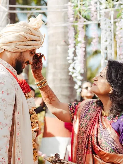 The mother of the groom performs a traditional welcome ritual, a beautiful moment of acceptance and love.