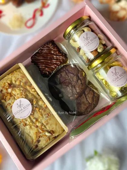 The 'Pyaar Bhaara' Rakhi hamper, beautifully arranged with a tea cake, brownie, cookies, and jars of nuts and chocolates.