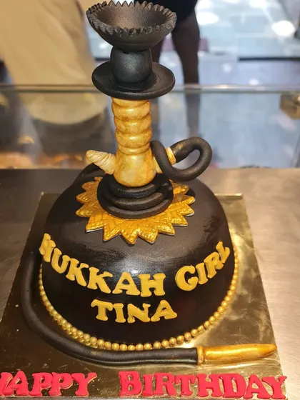 A unique hookah-themed cake for a special birthday. This sculpted cake is designed in black and gold, featuring a detailed, edible hookah pipe on top.