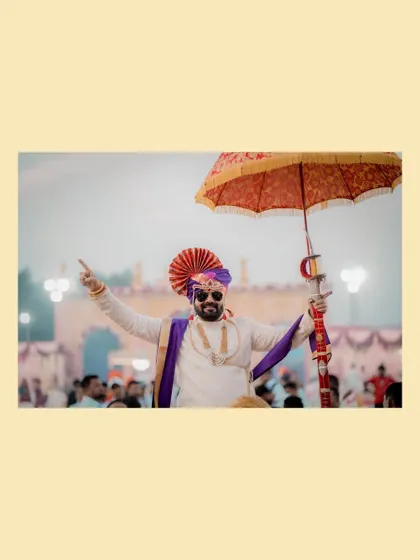 The groom makes a grand, celebratory entrance under a traditional umbrella, full of energy and excitement for his wedding.