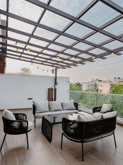 A stylish balcony retreat with a pergola. The comfortable outdoor furniture is perfect for relaxing, and the string lights add a warm and festive glow in the evenings.