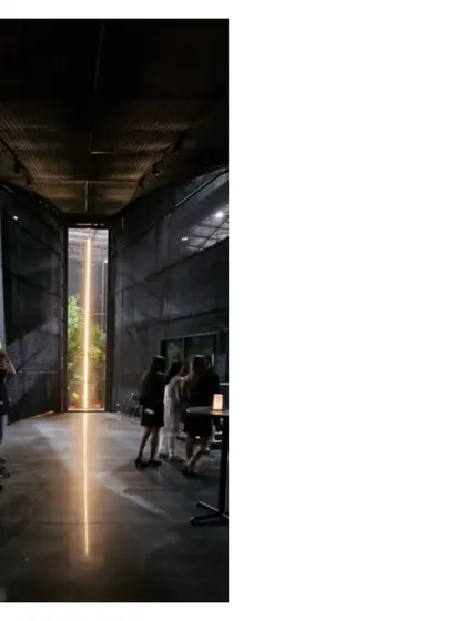 The interior of the Durall Pavilion, where a vertical line of light acts as a focal point. The dark, mesh clad space creates a dramatic atmosphere for showcasing products and hosting events.