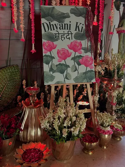 A closer look at the personalized mehendi welcome sign, surrounded by fresh tuberoses and brass lamps.