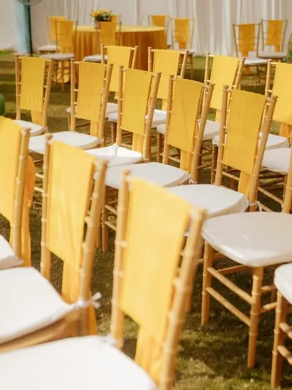 A wider view of the guest seating, showing how the rows of chairs with yellow sashes create a visually appealing pattern on the green lawn, leading towards the main event area.