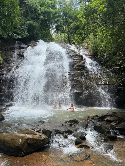 Two trekkers enjoying a moment of solitude and joy in the waterfall's pool. Even in a group, you can find your own peaceful connection with nature.