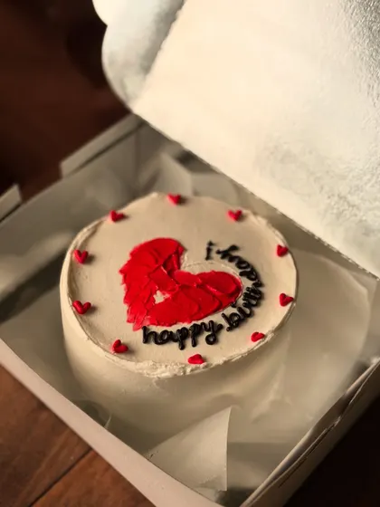 A simple and sweet birthday cake with a large, textured red heart in the center. The cake is surrounded by tiny red hearts, making it a lovely romantic gift.