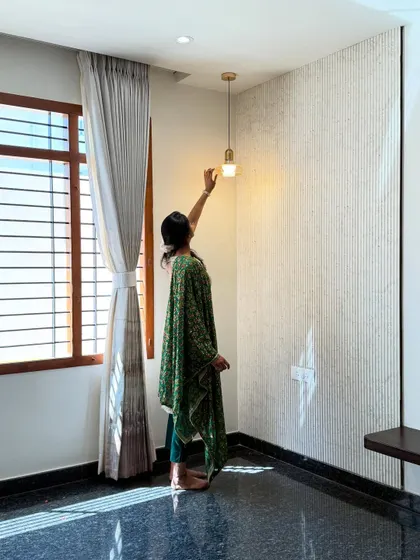 Here, our designer makes a final adjustment to the lighting on a textured wall. The combination of the fluted surface and the warm pendant light creates beautiful shadows and adds a layer of depth to the room.