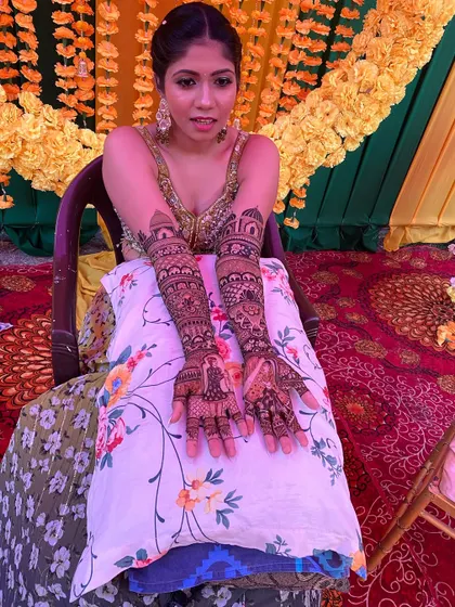 This bride is ready for her mehandi ceremony, showing off her full-arm henna. The design includes architectural domes and a beautiful portrait on the palm.