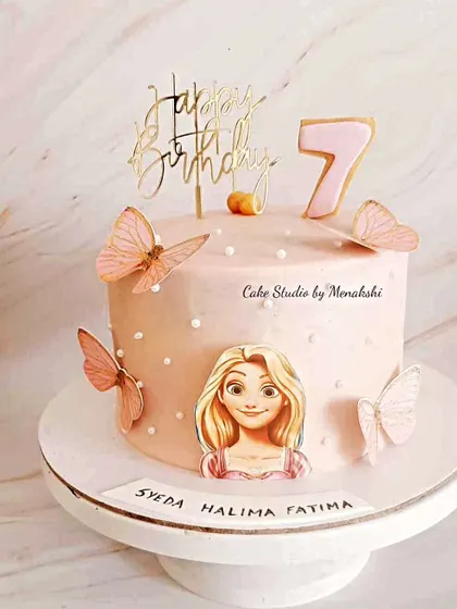 A pretty Rapunzel themed cake for a 7th birthday. This pink cake is decorated with butterflies and a picture of the long-haired princess.