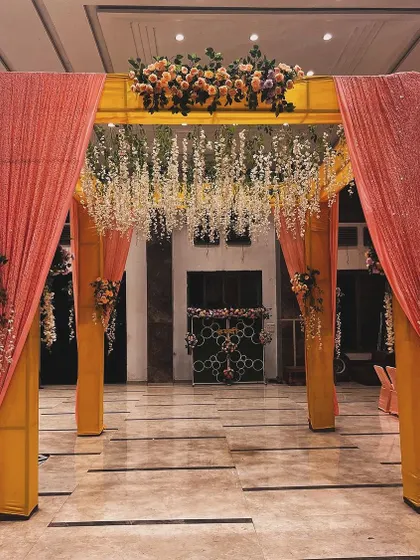 A closer view of the indoor mandap entrance. The sequined peach drapes and hanging white flowers add a touch of glamour to the traditional structure.