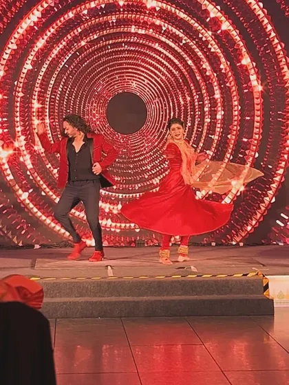 A joyful action shot from a live duet performance on a grand stage.