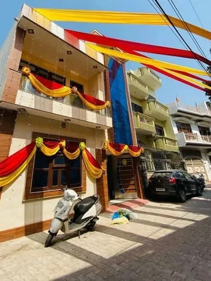 A full view of a house decorated with red and yellow drapes for a wedding celebration, covering the balconies and roofline.