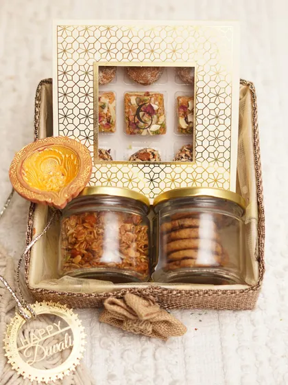 Our 'Assorted Delight Hamper' includes handmade sweets, granola, chocolate chunk cookies, and an earthen diya.