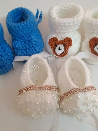 A small collection of my baby booties, showing the variety of styles I can create, from simple blue ones to bear-themed and pearl-studded designs.